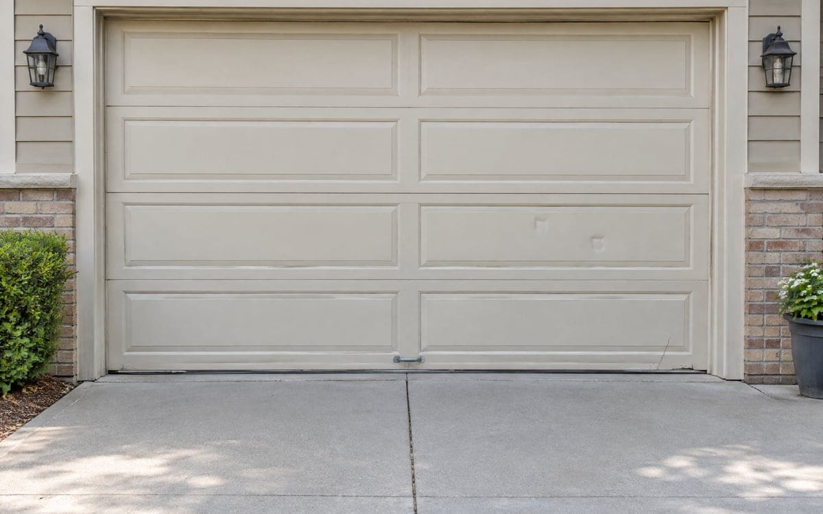 An older tan two-car door with small cracks in its panels, a repair or replace garage door question.