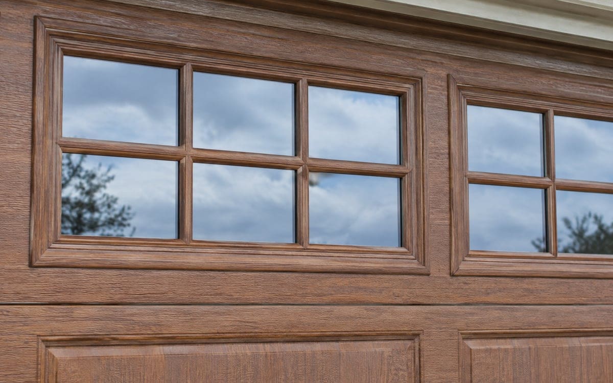 Divided-lite windows across the top section of a wood-look door, one choice in a garage door installation.