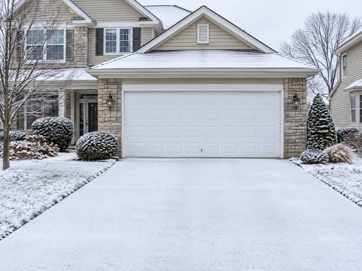 A closed white two-car door under fresh snow, the kind of morning a garage door won't open.