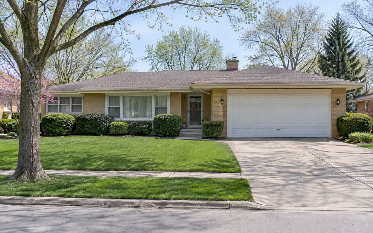 Garage door repair on a 1960s brick ranch with a white two-car attached garage door.