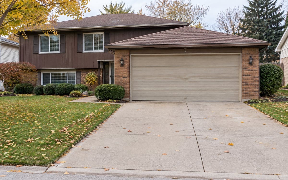 Repair or replace garage door, Barrington: a faded two-car door on a split-level, driveway running out to the street.